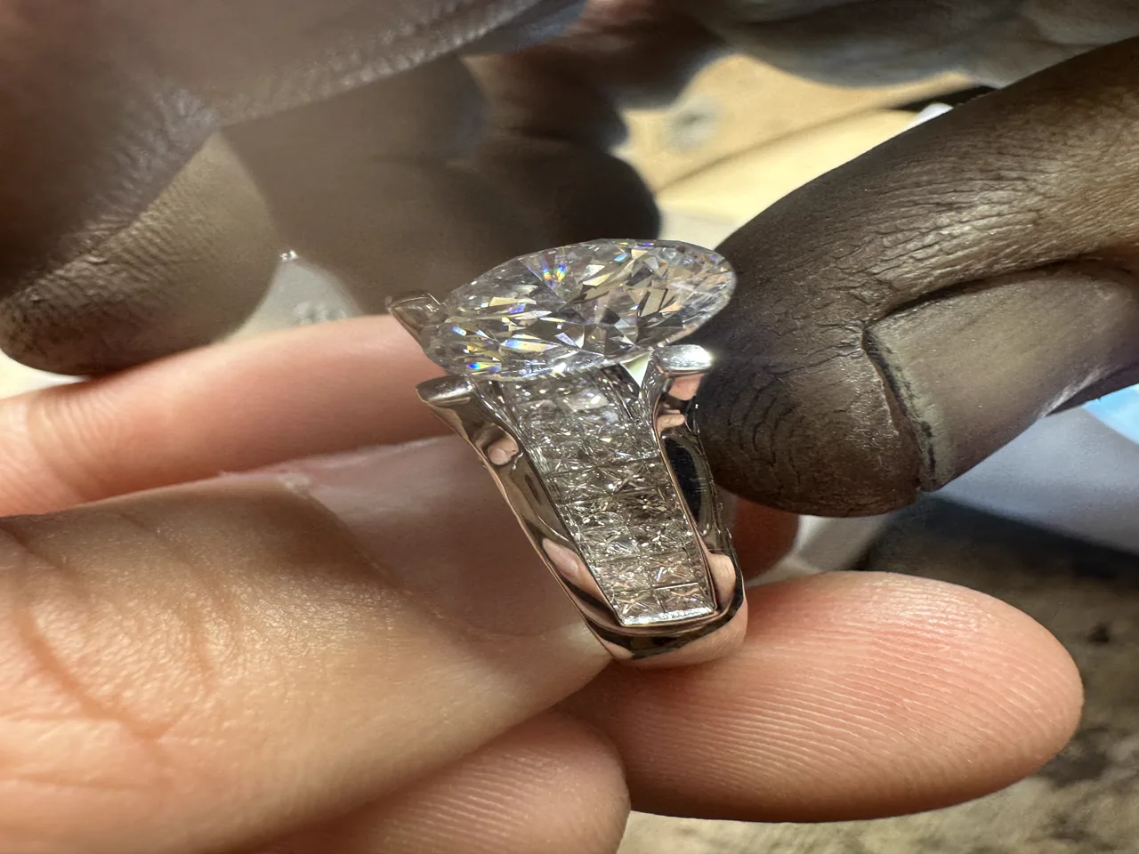 Diamond ring held at a jeweler's bench, showing clean hand-finished work.