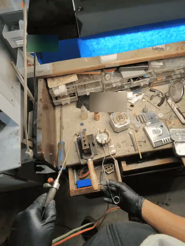 Goldsmith working a torch over a well-used custom jewelry bench.